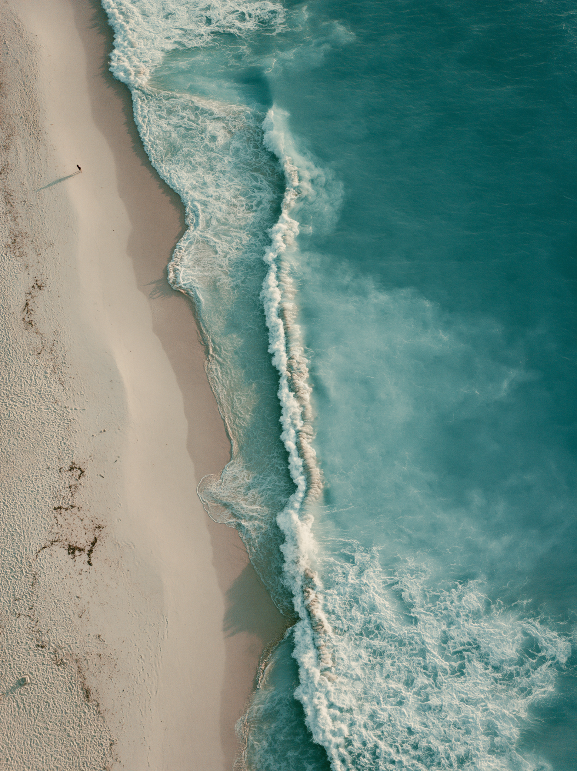 Aerial ocean rolling onto sand